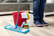 Un homme debout à côté de produits de nettoyage de sols