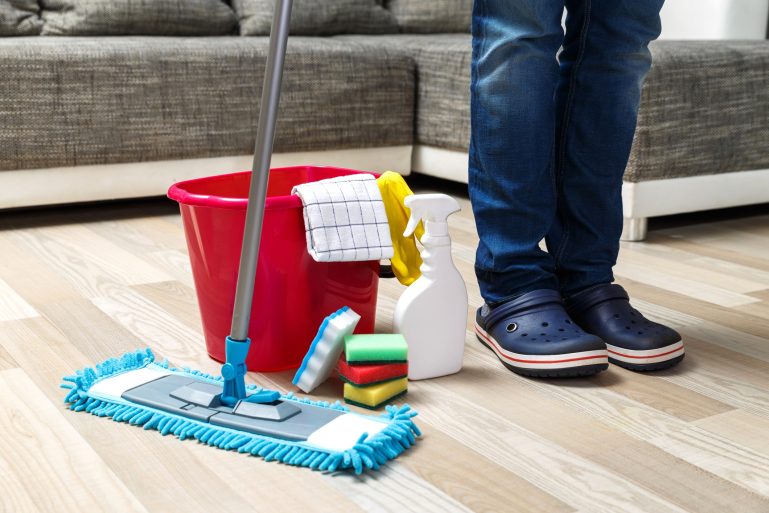 Un homme debout à côté de produits de nettoyage de sols