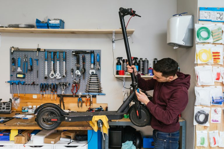 Un homme dans un atelier en train de réparer une trottinette électrique