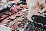 Un consommateur choisit une barquette de viande rouge dans un magasin