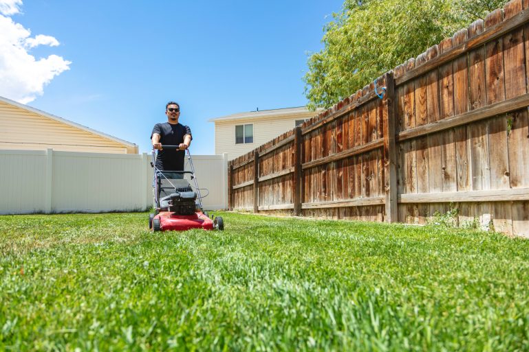 Un voisin passe sa tondeuse thermique dans son jardin