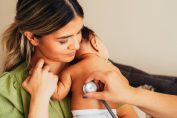 bébé dans les bras de sa maman examiné par un médecin