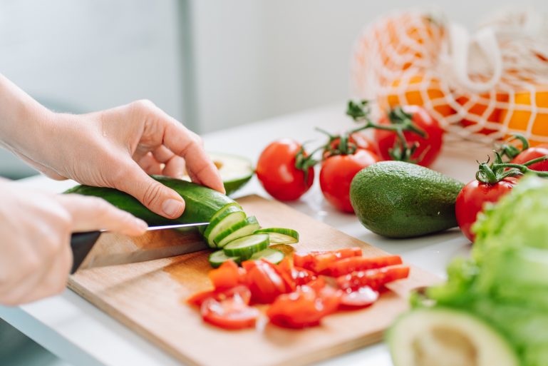 Une femme en train de découper des légumes pour une salade
