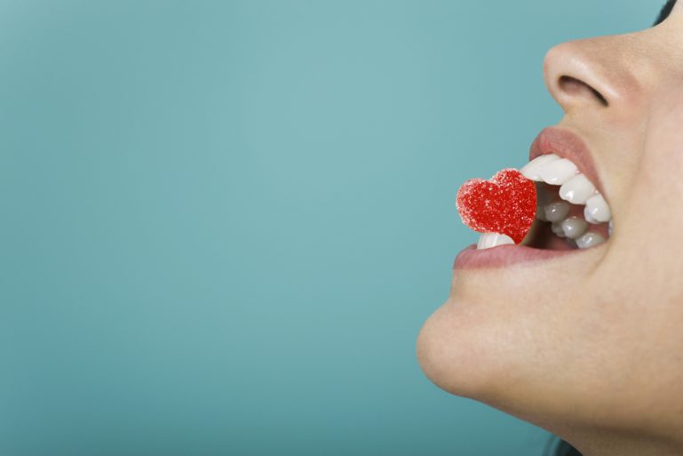 Une femme tient un cœur en bonbon entre ses dents