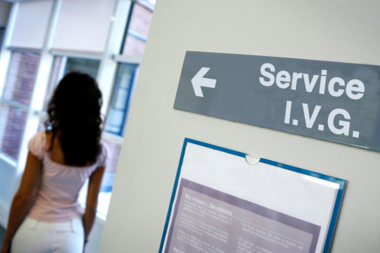 Femme de dos à côté d'un panneau "Service I.V.G"
