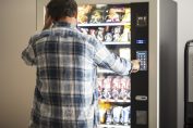 Un homme devant un distributeur atomatique