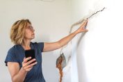 Une propriétaire examine une fissure sur un mur intérieur