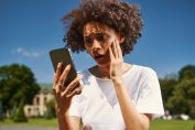 Une jeune femme affolée en lisant son smartphone.