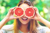 Une femme tenant des demi-pamplemousses devant ses yeux