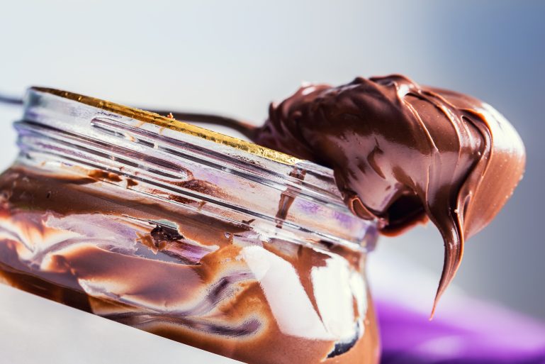 Une cuillère de pâte à tartiner sur un pot de Nutella