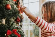 Une petite fille décore un sapin de Noël