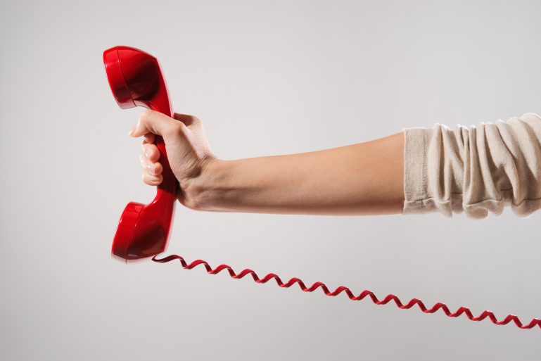 Un téléphone rouge tenu à bout de bras