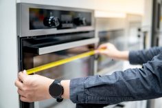 Un homme mesure un four dans un magasin