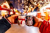 Deux personnes trinquent avec des mugs dans un marché de Noël