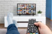 Une personne télécommande à la main devant sa TV connectée