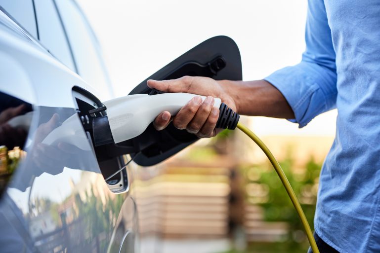 Homme en train de recharger sa voiture électrique