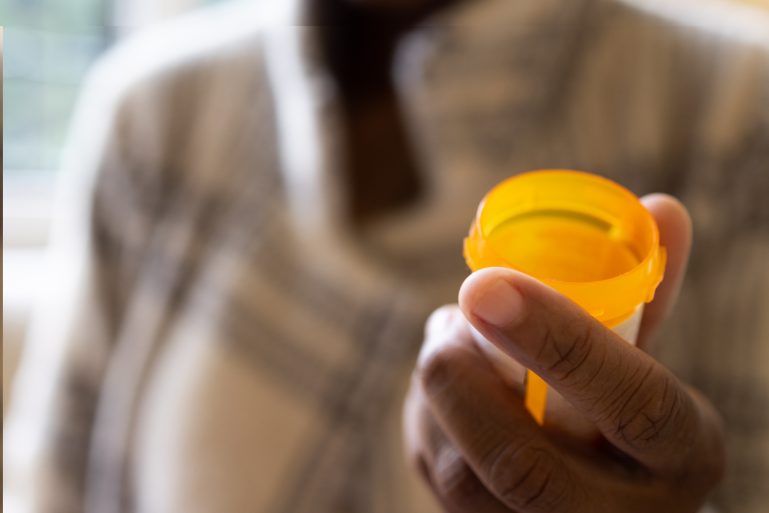 Femme tenant une boîte de médicament vide