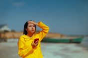 Jeune femme en imperméable par beau temps soupirant devant son téléphone