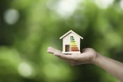 Une petite maison en bois dans une main avec les notes du DPE