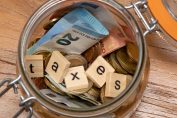 Un bocal rempli d'argent et des lettres formant taxes