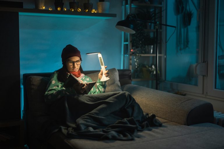 Une femme sans électricité dans son appartement lit avec une torche