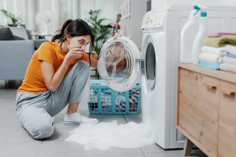 Une femme catastrophée devant son lave-linge en panne
