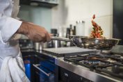 Un chef cuisine avec une poêle en Inox
