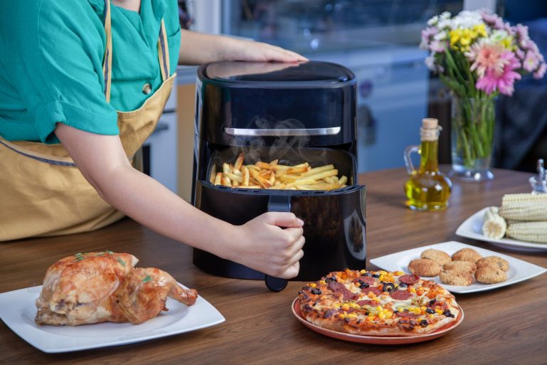 Une cuisinière sort le tiroir de son air fryer