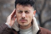 Un homme grimace de mal et se tient les oreilles