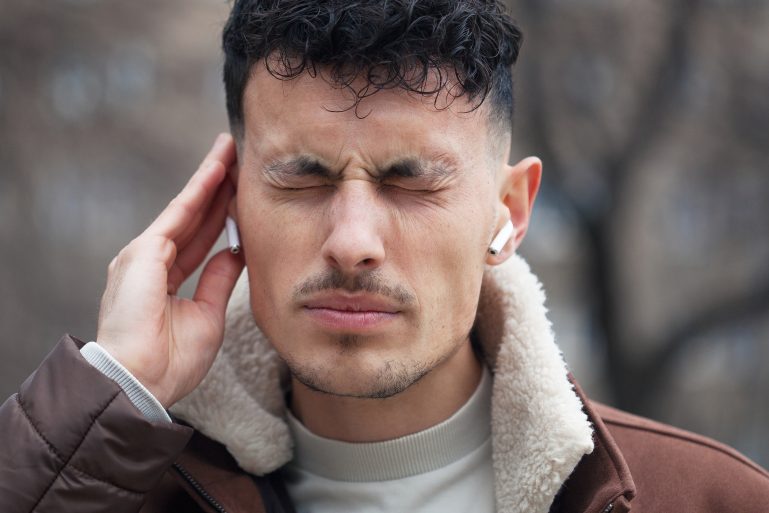 Un homme grimace de mal et se tient les oreilles