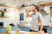 Un homme boit un shaker de protéines dans sa cuisine