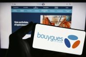 Une personne tient un téléphone avec le logo Bouygues