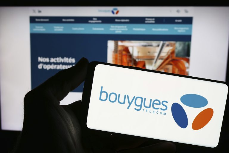 Une personne tient un téléphone avec le logo Bouygues