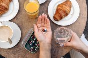 Des compléments alimentaires dans une main lors d'un petit déjeuner
