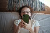 Une enfant consulte son smartphone sur un lit