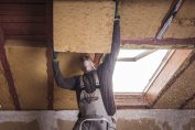 Un homme isole le toit d'une maison