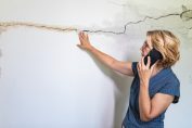 Une femme regarde un mur fissuré