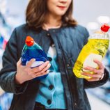 Une femme hésite entre deux produits nettoyants en agasins