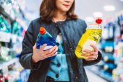 Une femme hésite entre deux produits nettoyants en agasins