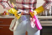 Une femme tient 2 spray nettoyants dans son dos