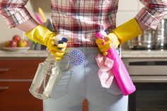 Une femme tient 2 spray nettoyants dans son dos