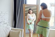 Une jeune femme mesure sa taille en souriant
