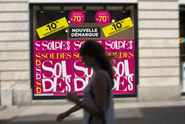 ne femme passe devant une vitrine où sont annoncés les soldes