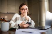 Une femme doute en consultant sa facture sur mobile