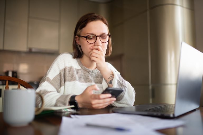 Une femme doute en consultant sa facture sur mobile
