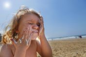 Un enfant se barbouille le visage de crème solaire