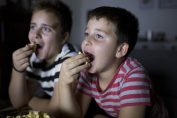Deux garçons mangent devant la télévision
