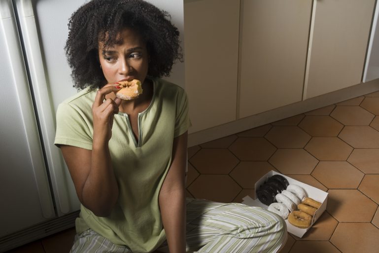 Une femme mange un gâteau assise par terre