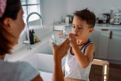 Un petit garçon boit un verre d'eau