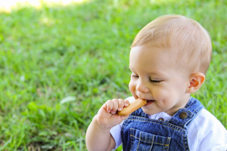 Un bébé avec un gâteau industriel a la bouche